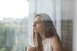 © Javier Pardina/Stocksy - Portrait of woman taking tea near to window.
