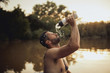 © Branko Starcevic/Stocksy - Man pouring water on his face from bottle.