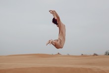Unrecognizable Female Jumping By Desert Landscape