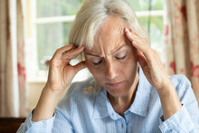 Senior Woman At Home Suffering With Migraine Headache