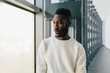 © MyMicrostock/Stocksy - Young black man with pensive expression looking out window