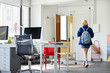 © ALTO IMAGES/Stocksy - Professional With Backpack Walking In Office