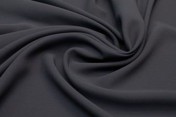 Black silk fabric in artistic layout. Texture, background, pattern.