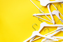 White clothes hangers on yellow background with copy space. Flat lay. Top view. Minimalism style. Creative layout. Fashion, store sale, shopping concept. Banner for feminine blog