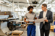 © Drazen - Company manager and black manual worker talking while analyzing project plans in a factory.