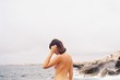 © Lucas Ottone/Stocksy - Shirtless woman standing on seashore