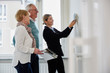 © Maskot - Smiling female estate agent showing color samples to retired couple at new home