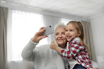 Canvas Print - Cute girl and her grandmother taking selfie  at home