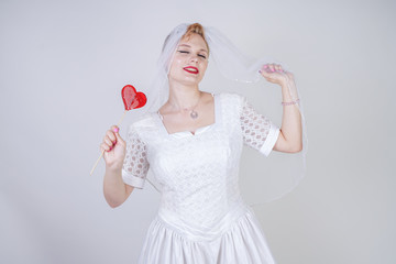 pretty curvy adult woman with short hair wearing long vintage wedding dress with sun style skirt. young caucasian bride with veil on white studio background alone.