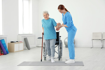 Wall Mural - Professional physiotherapist working with elderly patient in rehabilitation center