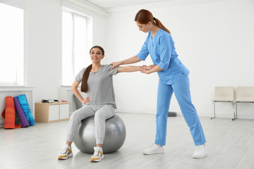 Canvas Print - Professional physiotherapist working with female patient in rehabilitation center