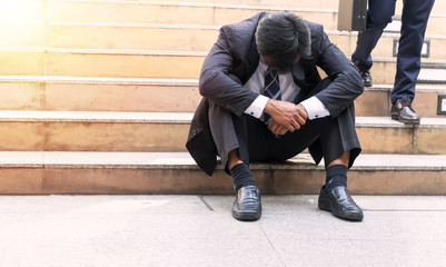 Concept business people bankruptcy and unemployment problem. Business men failure and debt sitting on the stairs with holding his hands. Unemployed businessman frustrated and desperate to find work.