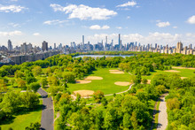 Aerial View Of The Central Park In New York With Golf Fields And Tall Skyscrapers Surrounding The Park.