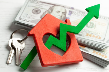 Up arrow and house with money on white wooden background. Market growth in real estate prices