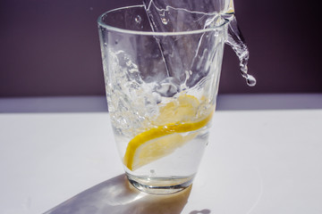 glass of water with lemon and ice on white background