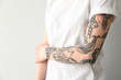 © Pixel-Shot - Stylish tattooed woman on light background, closeup