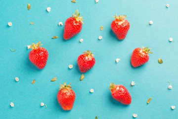 Strawberry creative pattern. Ripe red berry with green leaves on blue background