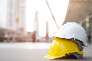 yellow and white hard safety wear helmet hat in the project at construction site building on concrete floor on city with sunlight. helmet for workman as engineer or worker. concept safety first. 