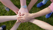 © emaria - Happy friends putting their hands on top of each other on the grass on the background