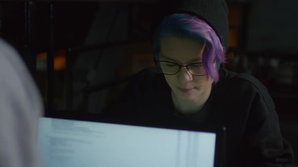 Wall Mural - medium shot of two young caucasian hipsters sitting at computers in front of each other and talking 