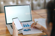 © jannoon028 - Business woman hand with Financial charts and mobile phone over laptop on the table .