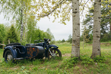An Old, Rusty Motorcycle With A Sidecar Stands Alone In The Woods