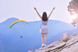 © Dmytro - Paragliding. Happy girl takes hands up and enjoys beautiful mountain views with paraglider. She breathes in the fresh mountain air. Feeling fresh and freedom concept.