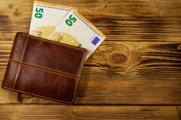 Wallet and fifty euro banknotes on wooden background