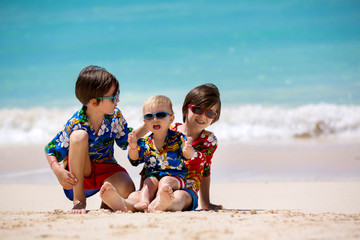 Wall Mural - Happy beautiful fashion family, mom and children, dressed in hawaiian shirts, playing together on the beach