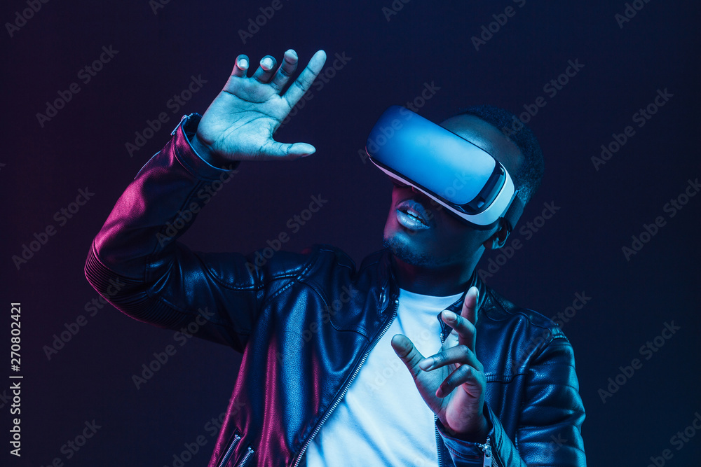 Young african man wearing virtual reality goggles with hands up ...