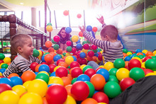 Young Mom Playing With Kids In Pool With Colorful Balls