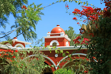 Vivid red and white dome of a Peruvian building against sunny clear sky, Huacachina oasis town, Ica region, Peru