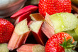 Close up of Pieces of Raw and Freshly Cut Rhubarb and Strawberries on Dark Rustic Background