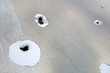 metal background punched by many bullets, metal sheet with bullet holes, closeup