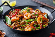 Stir Fry Noodles With Vegetables And Shrimps In Black Iron Pan. Slate Background. Close Up.