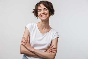 Sticker - Image of cheerful woman in basic t-shirt smiling at camera while standing with arms crossed