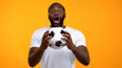 © motortion - Young Afro-American male with soccer ball emotionally cheering for national team