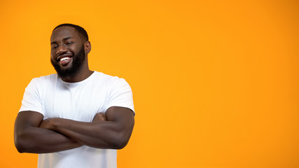 Wall Mural - Handsome Afro-American man standing with hands crossed, looking at camera