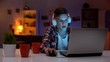 © motortion - Addicted teenager playing computer games on laptop, lot of cups standing on side
