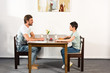 © LIGHTFIELD STUDIOS - father and son looking at each other during breakfast in kitchen