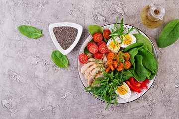 Plate with a keto diet food. Cherry tomatoes, chicken breast, eggs, carrot, salad with arugula  and spinach. Keto lunch. Top view