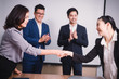 © PRASERT - Business people shaking hands, between meeting in seminar room