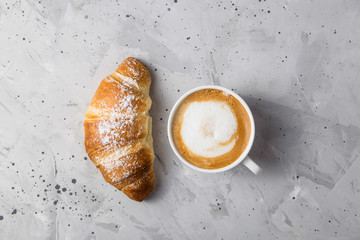 Beautiful and simple traditional French breakfast of fresh croissant and a cup of cappuccino