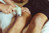 Fototapeta Zachód słońca - Physicaltherapist using ultrasound probe on patient  knee for release pain.