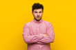 © luismolinero - Man with curly hair over isolated yellow wall keeping arms crossed