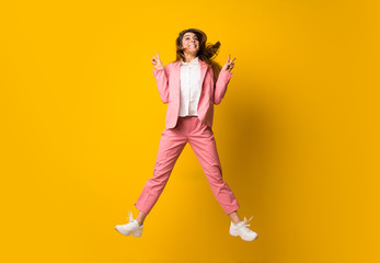 Young woman jumping over isolated yellow wall