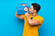 © luismolinero - Handsome man over blue background holding a radio
