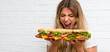 Blonde woman eating a giant sandwich