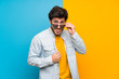 © luismolinero - Handsome over isolated colorful background with glasses and surprised