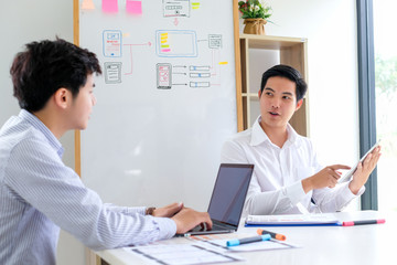 Wall Mural - two asian men are working together to design websites and application on mobile phone.